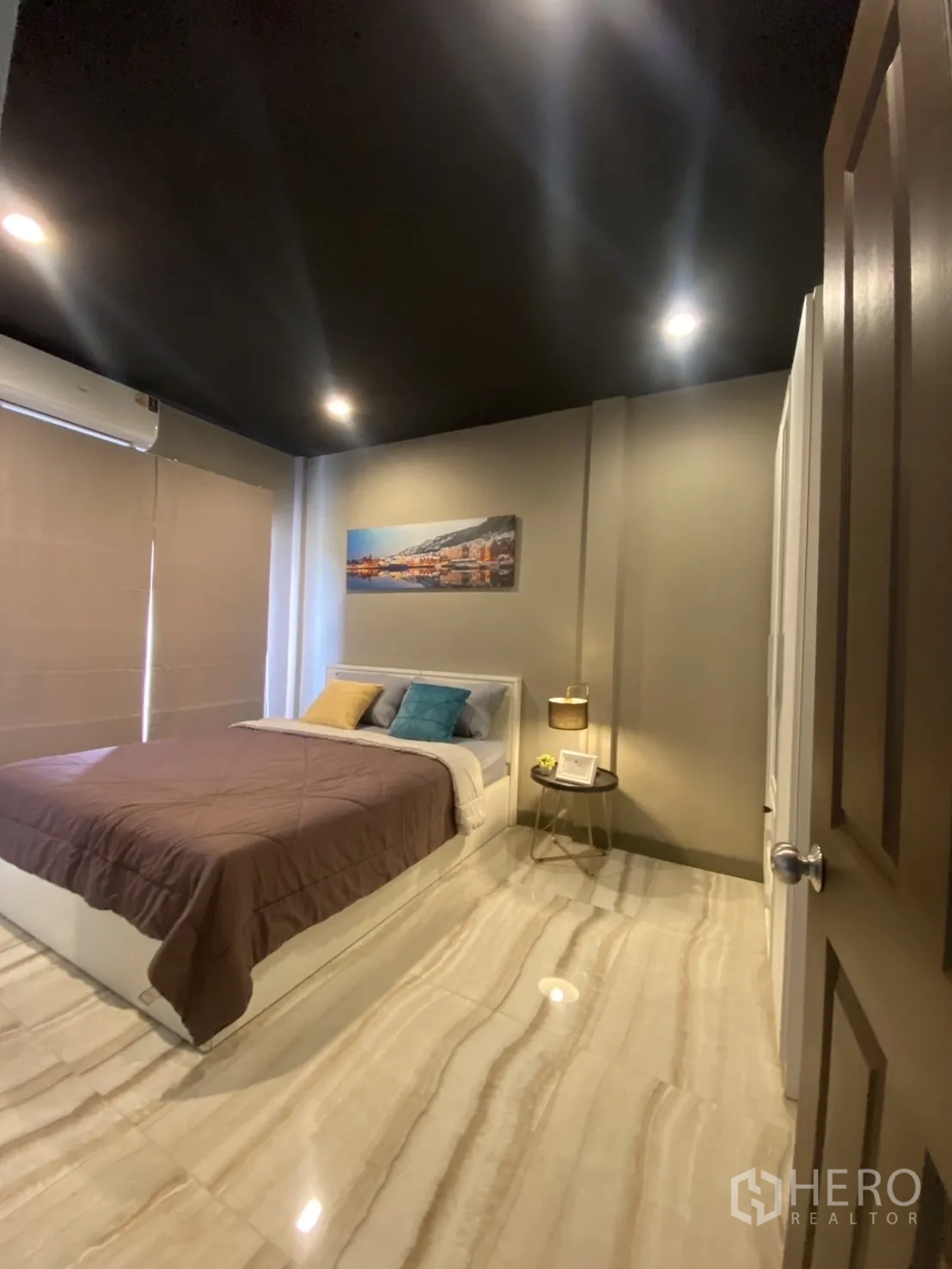 Townhouse for rent in Bang Kapi, Bangkok - Guest bedroom angle showing blinds, bedside table and glossy marble-look tiles.