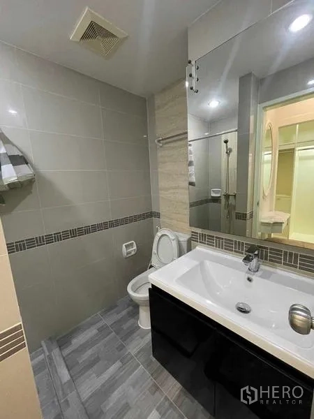 คอนโด ให้เช่า - ห้องน้ำสมัยใหม่ กระจกบานใหญ่ ตู้ใต้อ่าง และโถสุขภัณฑ์