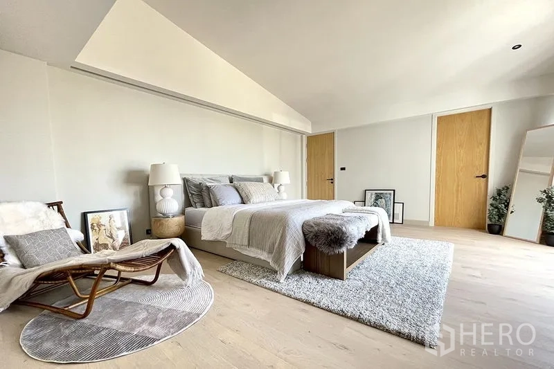 联排别墅 出售在Khlong Toei, Bangkok - 宽敞主卧，浅色木地板搭配休闲躺椅。
