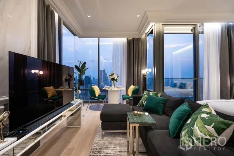 Condominium for rent in Bang Rak, Bangkok - Elegant open-plan living area with sectional sofa, TV console and floor-to-ceiling windows overlooking the Bangkok skyline.