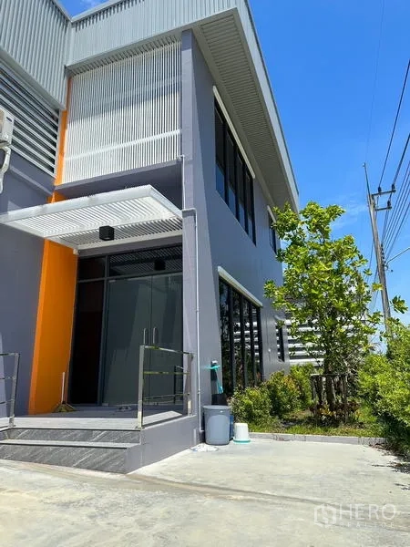 โรงงาน ให้เช่าหรือขายในLam Luk Ka, Pathum Thani - ทางเข้าออฟฟิศด้านหน้า ประตูกระจก กันสาดโลหะ และพื้นที่จัดสวน.