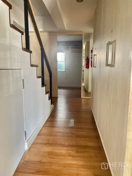 Home Office for rent or sale in Suan Luang, Bangkok - Hallway with wooden staircase and built‑in storage under the stairs.