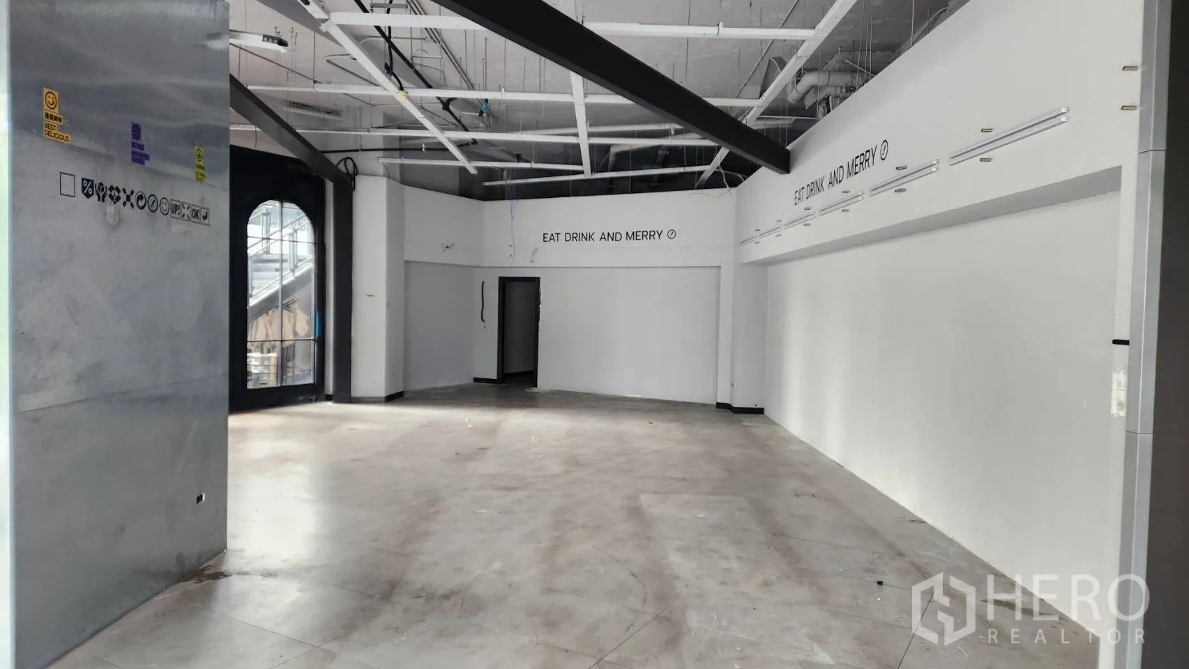 พื้นที่ขายปลีก ให้เช่า - พื้นที่ภายในโล่ง เพดานสูง เดินงานระบบเปลือย พื้นลายคอนกรีต และประตูทางเข้าโค้ง.
