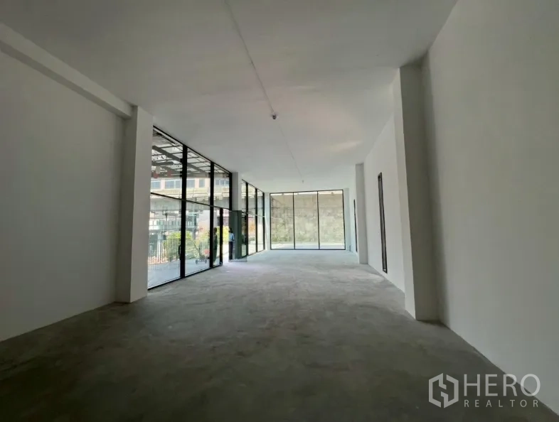 Retail Space for rent in Khlong Toei, Bangkok - Empty shell retail unit with high ceiling and floor-to-ceiling glass frontage allowing abundant daylight.