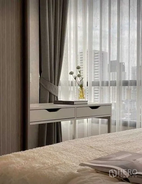 Condominium for rent in Watthana, Bangkok - Bedroom window with sheer curtains, dressing console and urban skyline beyond the glass.