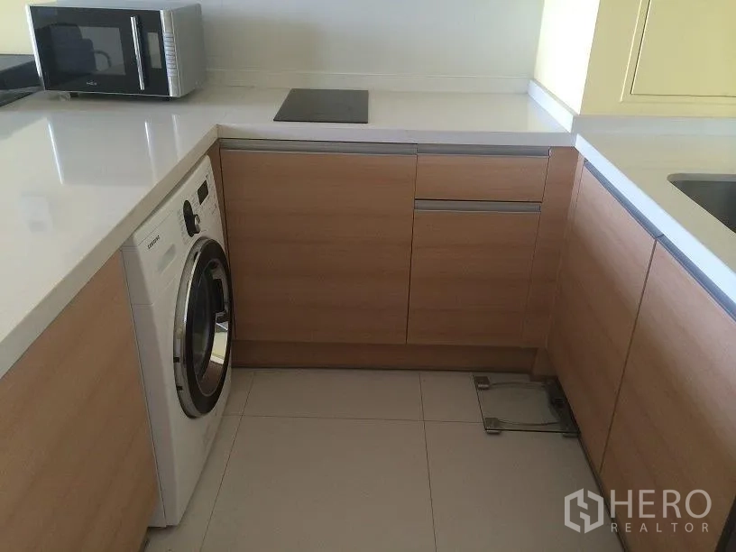 公寓 出租在Khlong Toei, Bangkok - U型厨房，配洗衣机、灶台与充足收纳柜。