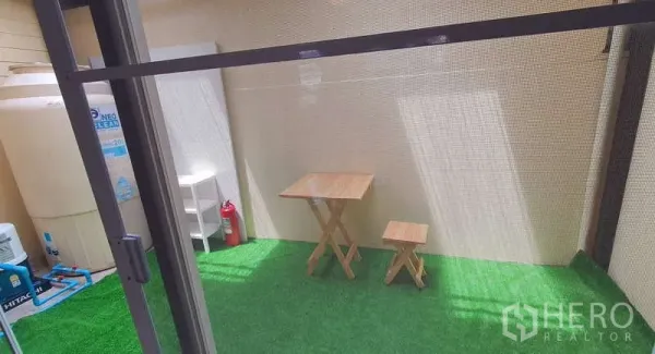 独立式住宅 出租在Bang Phli, Samut Prakan - 带顶棚的人造草坪露台，配有小型木质餐桌与储物区。