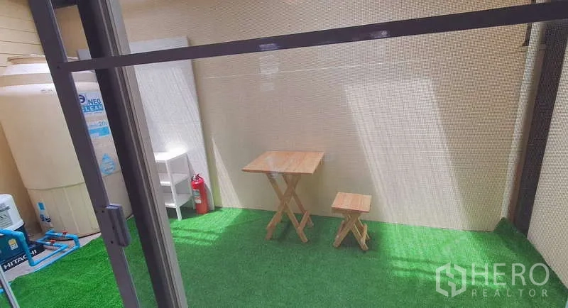 独立式住宅 出租在Bang Phli, Samut Prakan - 带顶棚的人造草坪露台，配有小型木质餐桌与储物区。