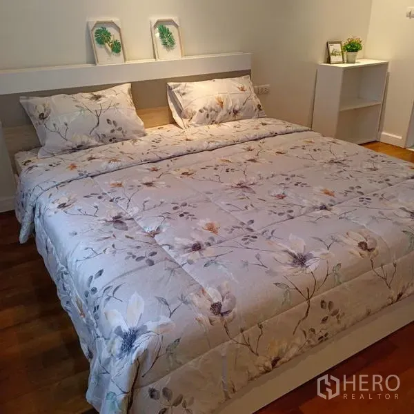 Condominium for rent in Watthana, Bangkok - Master bedroom with king bed, floral bedding, wood flooring and wall shelf in a Watthana condo.