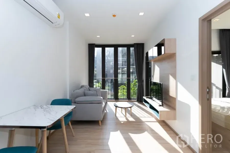 คอนโด ให้เช่าในWatthana, Bangkok - ห้องนั่งเล่นสว่าง ผนังกระจกเต็มบาน ระเบียง โซฟา และชั้นทีวี มองเห็นสวนสีเขียว