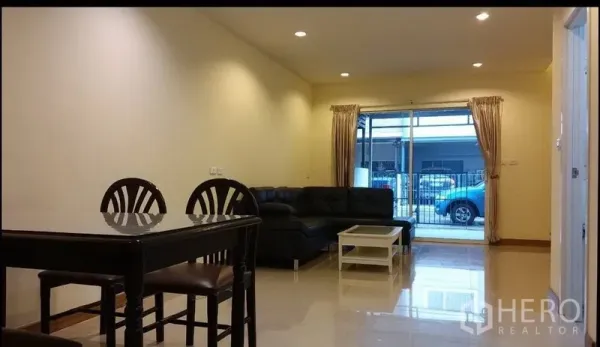 ทาวน์เฮาส์ ให้เช่าในSuan Luang, Bangkok - ห้องนั่งเล่นและรับประทานอาหารสว่าง โซฟาหนัง โต๊ะทานข้าว และประตูกระจกเลื่อนเปิดสู่หน้าบ้านรั้วเหล็ก