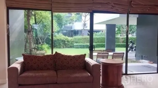 Detached House for rent in Bang Kapi, Bangkok - Sofa facing floor-to-ceiling windows with views of the landscaped garden and terrace.