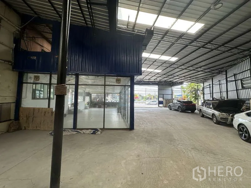 Warehouse for rent in Pak Kret, Nonthaburi - Covered loading bay with a glass-partitioned office area and on-site parking for vehicles.