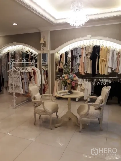 Shophouse for sale in Watthana, Bangkok - Boutique retail room with clothes racks, chandelier and small round table.