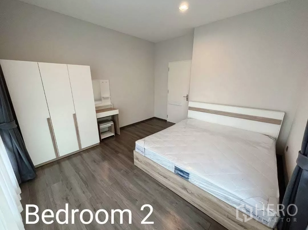 Detached House for rent in Samut Prakan - Spacious second bedroom with bed, wardrobe, dressing table, and laminate floors.