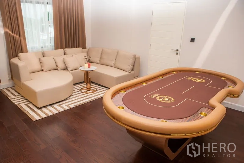 独立式住宅 出租或出售在Bangkok - 客厅配转角沙发与椭圆娱乐桌，木地板。