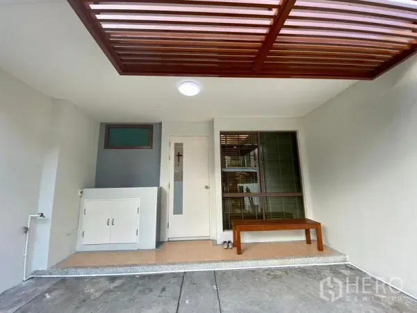 联排别墅 出租在Phra Khanong, Bangkok - 带木格栅顶棚的前院门廊与车位，并设长凳。