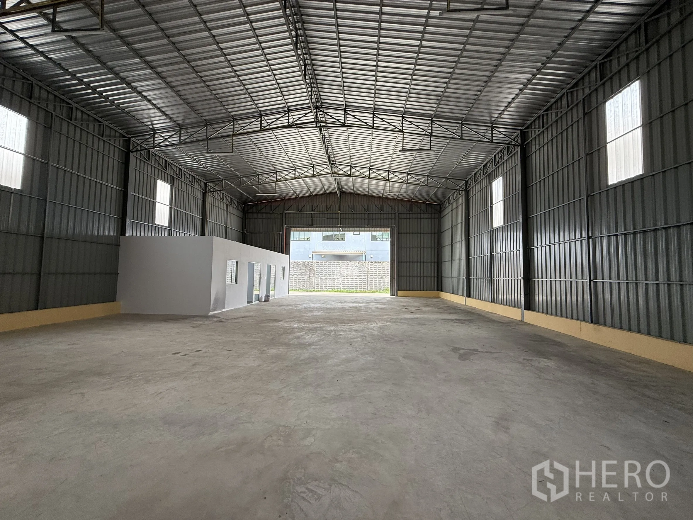 Warehouse for rent in Wang Thonglang, Bangkok - Large warehouse hall showing office partition and high windows.