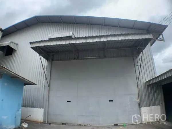 货栈 出租在Lak Si, Bangkok - 仓库立面的大型卷帘门与雨棚，方便卡车进出