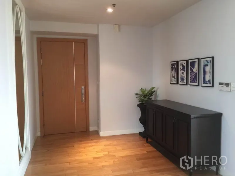 คอนโด ให้เช่าในKhlong Toei, Bangkok - โถงทางเข้ากว้างสว่าง ประตูไม้ ตู้คอนโซลสีเข้ม กรอบรูป และพื้นไม้ลามิเนตสีอ่อน