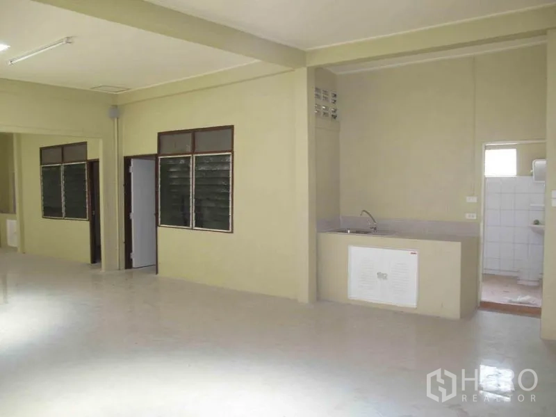 Warehouse for rent in Wang Thonglang, Bangkok - Utility zone with sink and doorway to tiled restroom inside the warehouse.