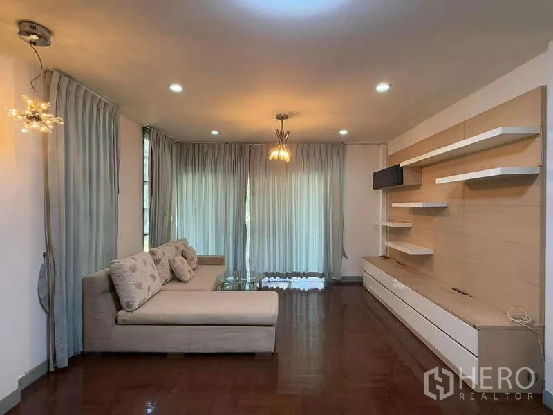 Detached House for rent in Bang Kapi, Bangkok - Living room with L‑shaped sofa, wall shelves and sheer drapes.