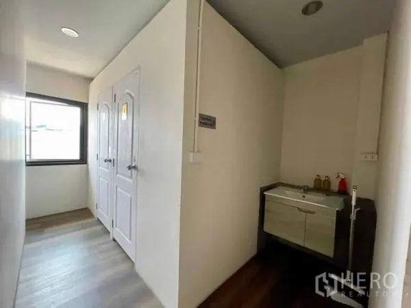 店屋 出租在Lat Phrao, Bangkok - 明亮走廊，双卫生间门与窗边洗手台。