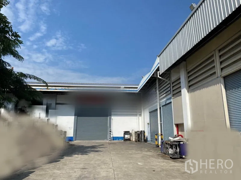 Factory for rent in Lam Luk Ka, Pathum Thani - Exterior loading yard with multiple roll‑up doors and wide concrete apron beside the factory building.