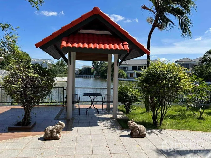 Detached House for rent in Bang Phli, Samut Prakan - Lakeside garden with a small red-roof pavilion and seating overlooking the water.