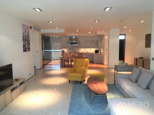 คอนโด ให้เช่าในKhlong Toei, Bangkok - ห้องนั่งเล่นแบบเปิดโล่งพร้อมโซฟา เก้าอี้สีเหลือง โต๊ะกลาง และมองเห็นครัวสมัยใหม่กับพื้นที่รับประทานอาหาร