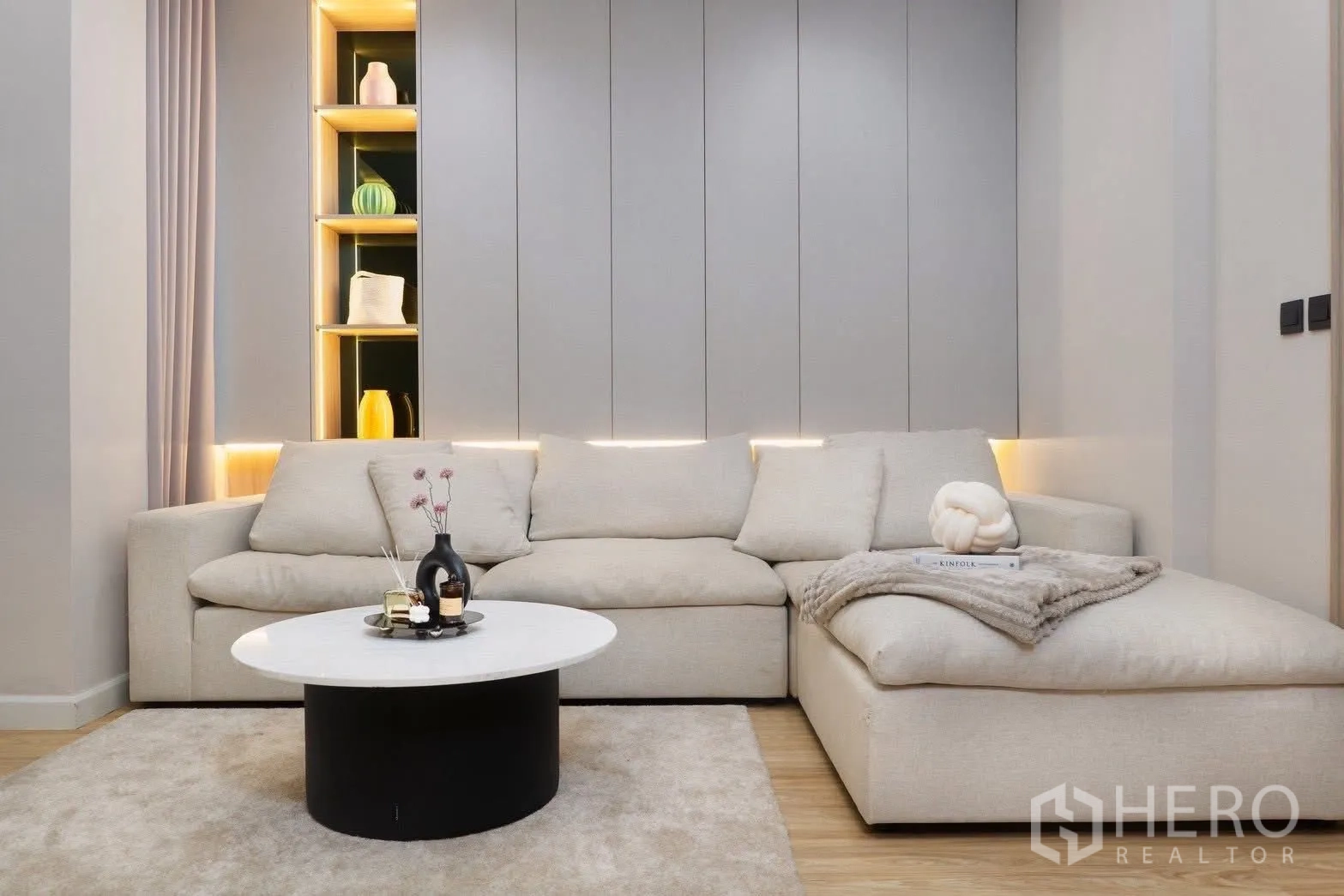 独栋房屋 for rent in Phra Khanong, Bangkok - 客厅配米色L形沙发、灯带展示壁龛与圆形茶几。