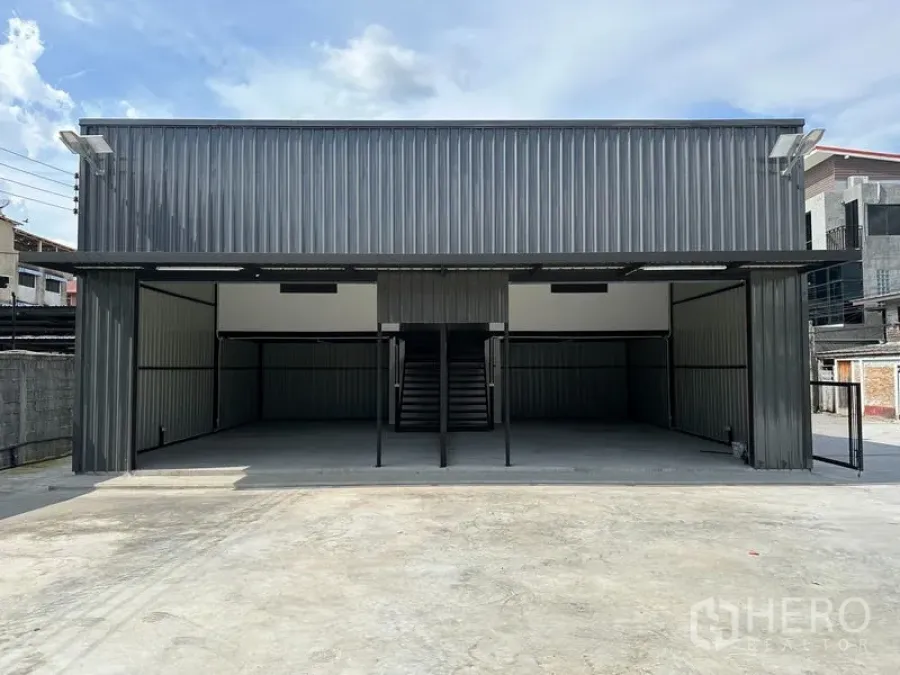 Warehouse for rent - Front view of metal-clad warehouse with central staircase, open bays and expansive driveway.