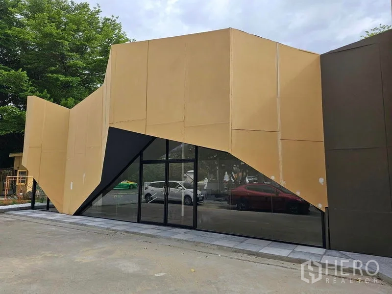 พื้นที่ขายปลีก ให้เช่าในPrawet, Bangkok - มุมใกล้ของยูนิตค้าปลีก โดดเด่นด้วยดีไซน์เหลี่ยมมุมและกระจกรอบด้าน พร้อมทางเดินปูพื้น