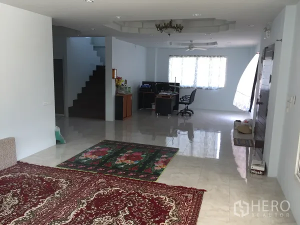 独立式住宅 出租在Saphan Sung, Bangkok - 开放式客厅，亮面瓷砖地面、地毯、楼梯、办公区、窗户与吊扇。