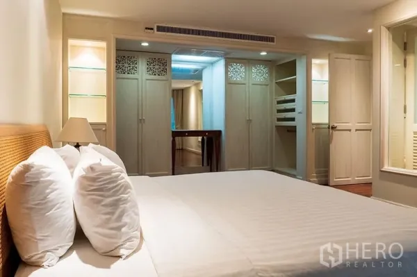 Apartment for rent in Bang Rak, Bangkok - Master bedroom with king bed, built-in wardrobes, dressing area and soft lighting.