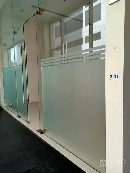 零售空间 出租在Khlong Toei, Bangkok - 室内走廊旁的玻璃店面，双开门与磨砂玻璃立面。