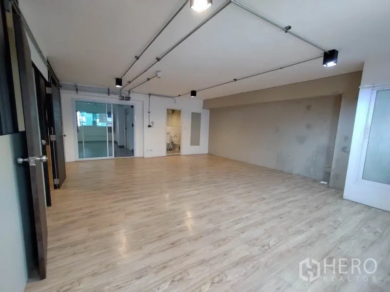 办公空间 出租在Phaya Thai, Bangkok - 开放式办公室，浅木纹地板，裸露管线与轨道灯，带滑动玻璃隔间。