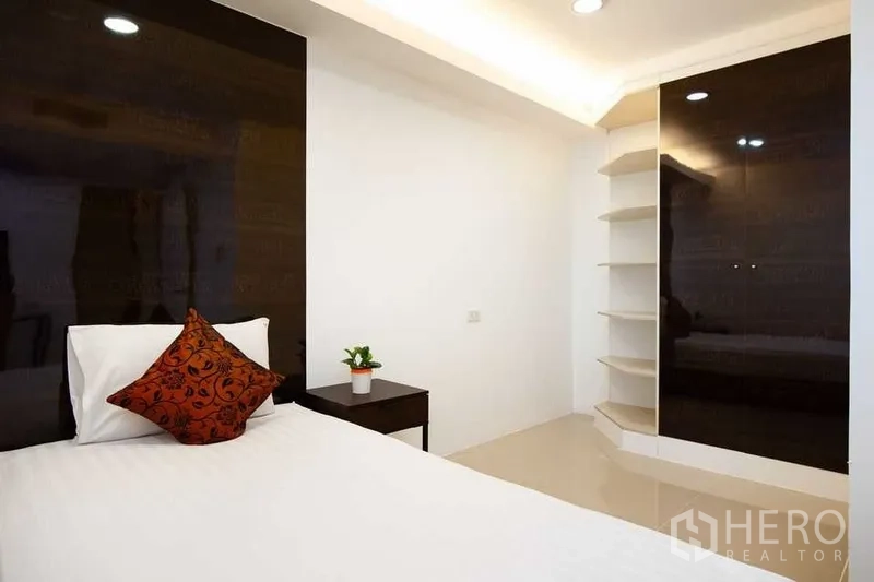 คอนโด ให้เช่าในKhlong Toei, Bangkok - มุมห้องนอนพร้อมชั้นบิวท์อินและตู้เสื้อผ้าไฮกลอสข้างเตียง