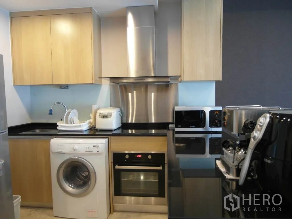 公寓 出租或出售在Sathon, Bangkok - 设备齐全的厨房，黑色台面，烤箱、抽油烟机、洗衣机、微波炉与咖啡机。