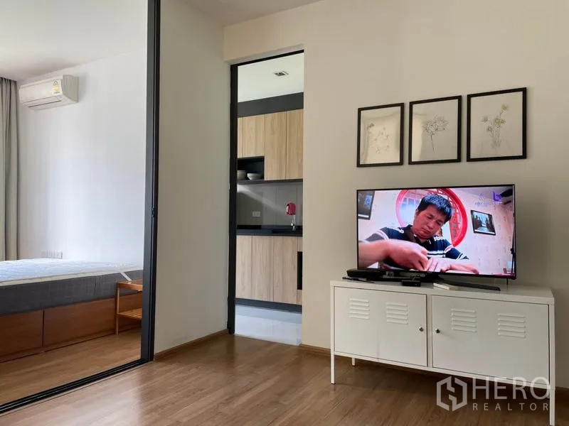 Condominium for sale in Watthana, Bangkok - Living area facing sliding door to the bedroom with a separate kitchen beyond.