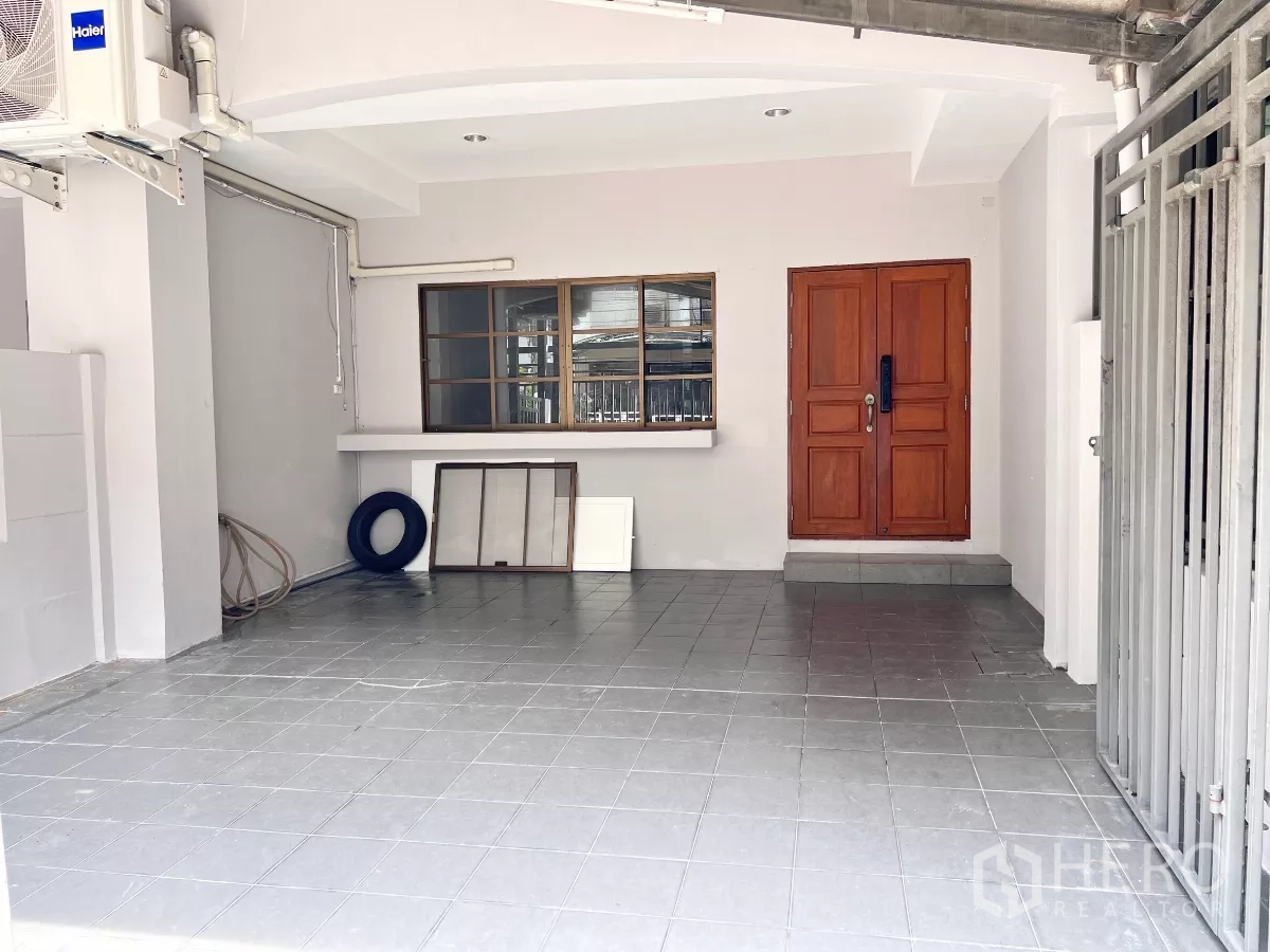 ทาวน์เฮาส์ ให้เช่าหรือขายในPhra Khanong, Bangkok - โรงรถชั้นล่างปูกระเบื้อง พร้อมประตูทางเข้าบ้านไม้สีน้ำตาล