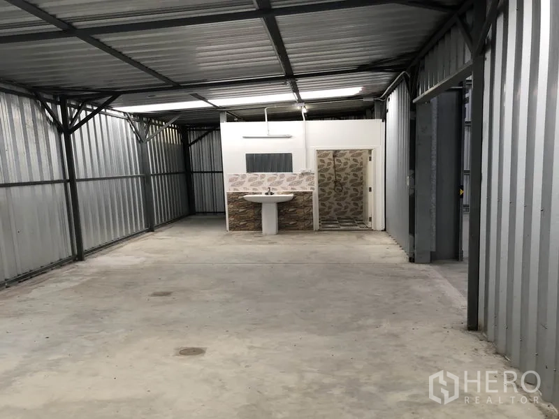 Warehouse for rent in Pak Kret, Nonthaburi - Covered ancillary area with concrete floor and washroom block within the warehouse.