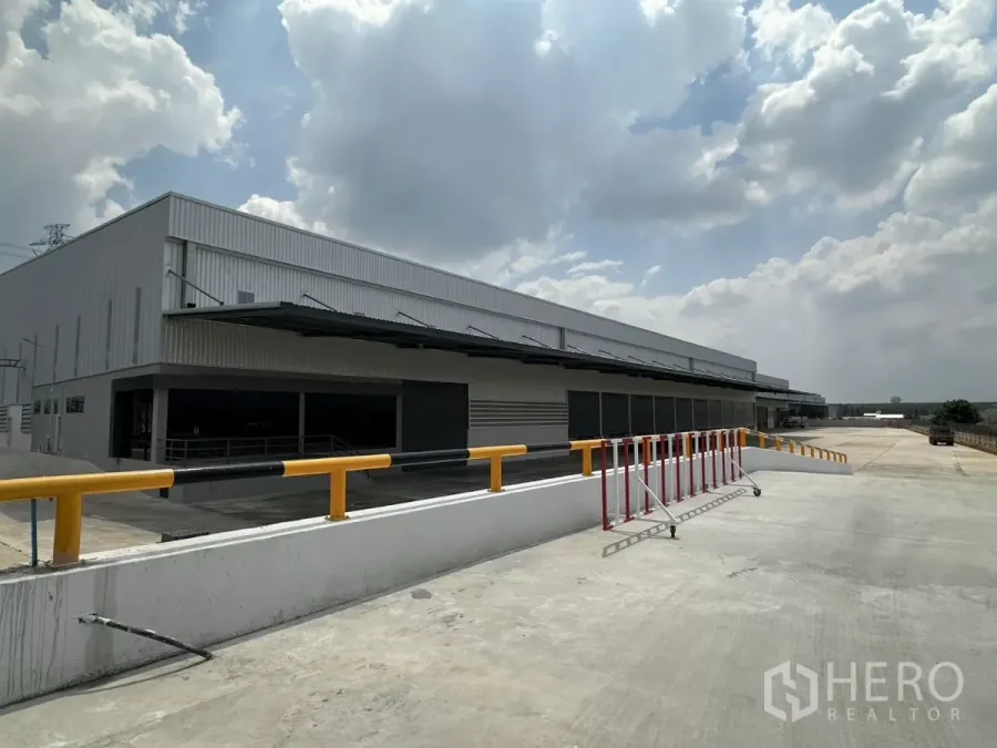 Factory for rent in Chon Buri - Modern steel-clad factory exterior with long covered loading docks, ramp and safety rail in Si Racha.