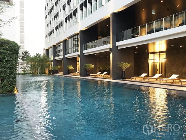 Condominium for rent in Pathum Wan, Bangkok - Condominium outdoor swimming pool with sun loungers along a modern building facade.