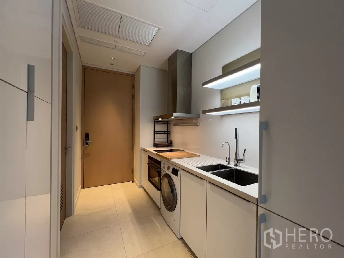 คอนโด ให้เช่าในPathum Wan, Bangkok - ครัวแบบทางเดินยาว มีอ่างล้างจานคู่ ชั้นวางของ และประตูทางเข้า