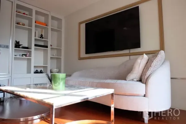 ทาวน์เฮาส์ ให้เช่าในKhlong Toei, Bangkok - ห้องนั่งเล่นสว่างพร้อมชั้นบิลต์อิน ทีวีติดผนัง โซฟาทรงโค้ง และโต๊ะหินอ่อน