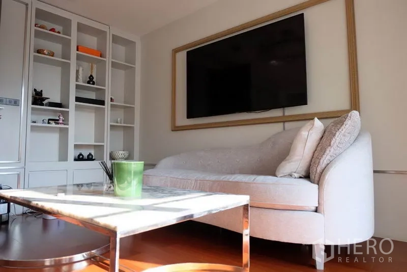 ทาวน์เฮาส์ ให้เช่าในKhlong Toei, Bangkok - ห้องนั่งเล่นสว่างพร้อมชั้นบิลต์อิน ทีวีติดผนัง โซฟาทรงโค้ง และโต๊ะหินอ่อน