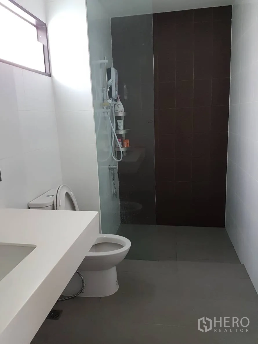Townhouse for rent or sale in Saphan Sung, Bangkok - Contemporary bathroom with large countertop, toilet and glass-partition walk-in shower.