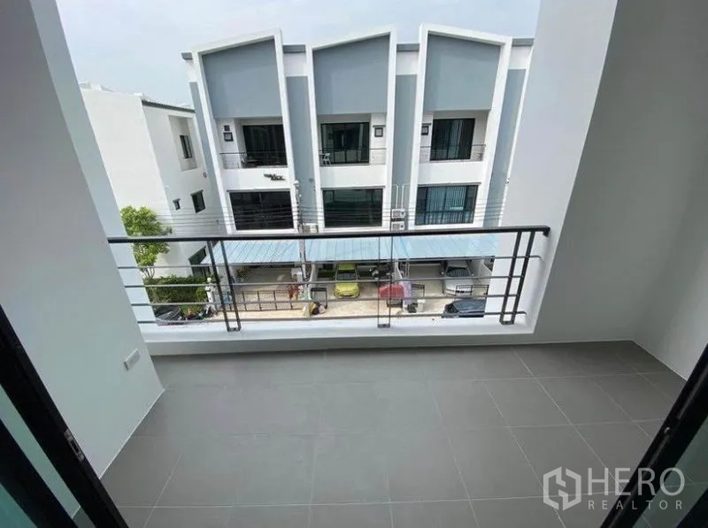 联排别墅 出租在Bang Na, Bangkok - 私家阳台灰色地砖，俯瞰现代联排别墅与车棚