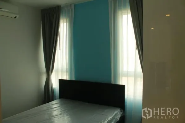 Condominium for rent or sale in Watthana, Bangkok - Bedroom with teal accent wall, double bed, large windows, and blackout curtains.